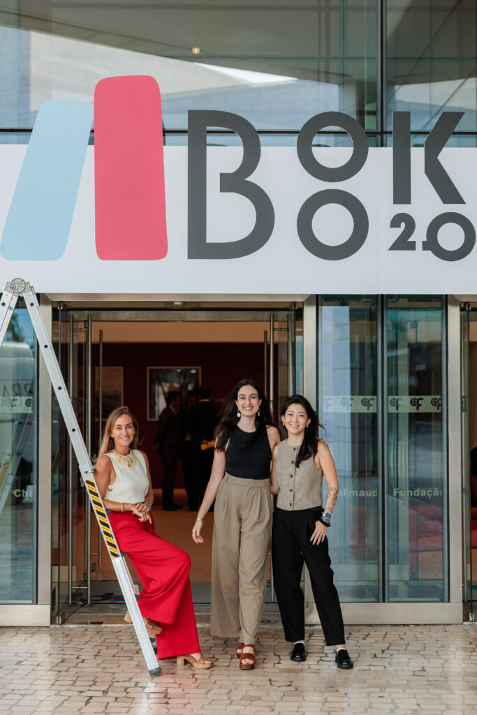 Three women on the steps of the Centro Cultural de Belem beneath the Book 2.0 banner